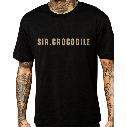 Black Sir Crocodile T-shirt with bold beige text worn by tattooed model