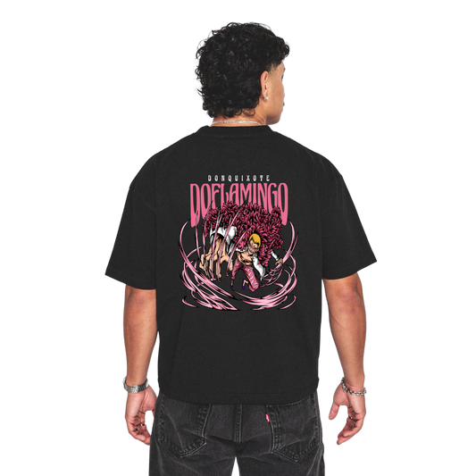Person wearing a Donquixote doflamingo black t-shirt with a colorful graphic design on the back, set against a white background.